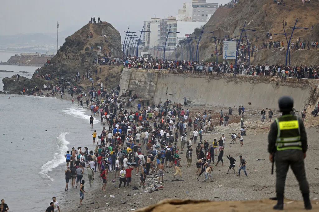 An official watches as people gather at the border between Morocco and Spain on July 31, 2026.